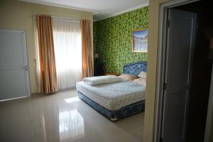 ein Schlafzimmer mit einem Bett in einem Zimmer mit grüner Tapete in der Unterkunft Griya Kayana Inn and Villas in Bogor
