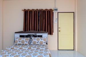 a bedroom with a bed and a yellow door at Beung Sampathuan Nakornchaisri Resort in Ban Laem Bua