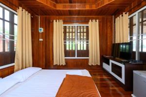 um quarto com uma cama, uma televisão e janelas em Beung Sampathuan Nakornchaisri Resort em Ban Laem Bua