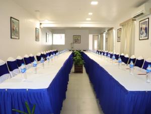 a row of long tables in a room with blue and white chairs at Niko Hotels in Cochin