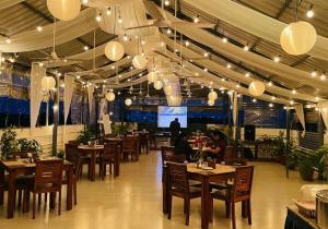 a restaurant with wooden tables and chairs and lights at Niko Hotels in Cochin