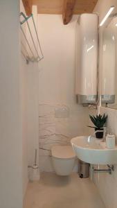 a white bathroom with a toilet and a sink at Sui Tetti di Valeggio - Holiday Apartment in Valeggio sul Mincio