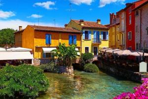 a group of colorful buildings next to a river at Sui Tetti di Valeggio - Holiday Apartment in Valeggio sul Mincio
