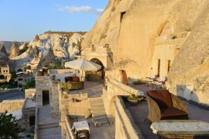 a patio with chairs and tables in front of a mountain at Village Cave House Hotel in Goreme
