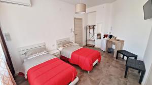 two beds in a white room with red sheets at MERIDIAN B&B in Siracusa