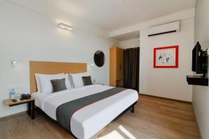 a hotel room with a large bed and a tv at Super Townhouse 124 Srm Kuppakonam Pudur in Coimbatore