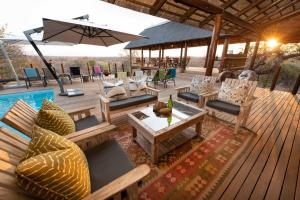 una terrazza con sedie, tavoli e ombrellone di Sausage Tree Safari Camp a Balule Game Reserve