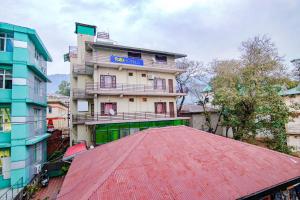 a building with a red roof in front of it at Hotel City Plaza in Dharamshala