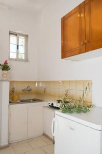 a kitchen with white cabinets and a white refrigerator at Kalofonos Studios in Zakynthos