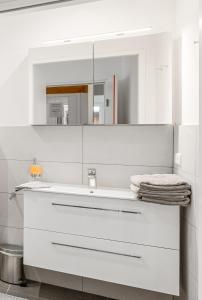 a white bathroom with a sink and a mirror at Hallstatt Lakeside Top 2 - Zimmer mit Gartenzugang in Hallstatt