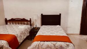 a bedroom with two beds and a lamp at Casa Adiel in Campeche