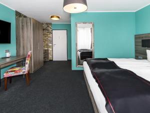 una camera con letto, scrivania e sedia di DORMERO Hotel München-Kirchheim Messe a Kirchheim