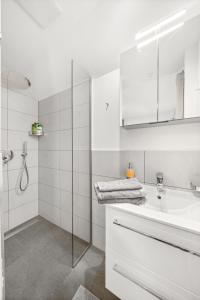 a white bathroom with a sink and a shower at Hallstatt Lakeside Top 4 - Zimmer mit Balkon in Hallstatt