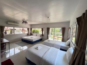 a bedroom with two beds and a desk and windows at Baan Pai Riverside Resort in Pai