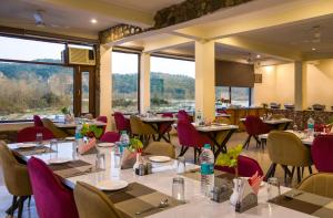 a restaurant with tables and chairs and large windows at Dee Fellows Riverside Resort in Garjia