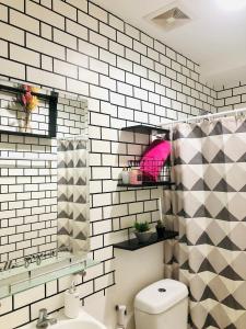 a bathroom with a toilet and a black and white tile wall at Azehr's Walk Up and Cozy Condo in Minglanilla