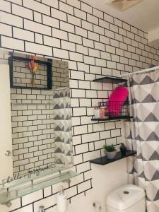 a bathroom with a white tiled wall and a toilet at Azehr's Walk Up and Cozy Condo in Minglanilla