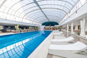 a large pool with white chairs and a glass ceiling at Grand Pasha Lefkosa Hotel & Casino in North Nicosia