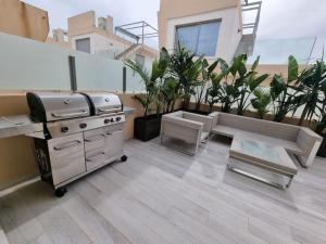 a rooftop patio with a grill and potted plants at A modern villa with pool and sea view in Pilar de la Horadada