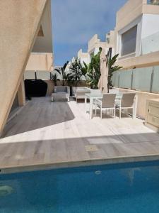 a patio with a pool and chairs and a umbrella at A modern villa with pool and sea view in Pilar de la Horadada