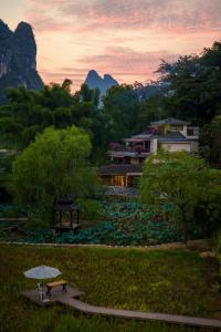 a building with a picnic table in a park with a sunset at The Apsara Lodge in Yangshuo
