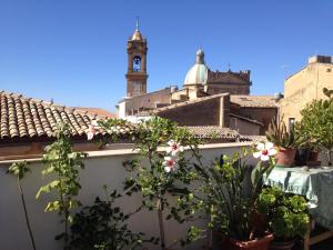 a white wall with potted plants and a clock tower at Il Piccolo Attico in Caltagirone