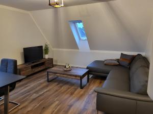 a living room with a couch and a tv at Krokusstr. 27A, Norden-Norddeich in Norden