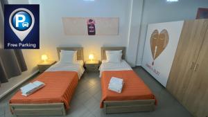 2 bedden met oranje lakens in een kamer bij Patras Romeο House in Patra