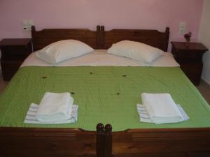 Una cama con sábanas verdes y toallas blancas. en Hellen Studios en Megali Ammos