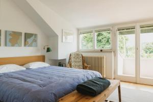 a bedroom with a bed and a chair and windows at Villa Fluggi in Merano