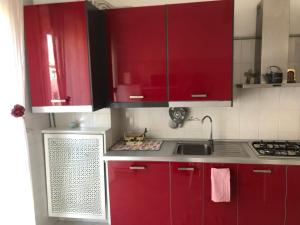 una cocina con armarios rojos y fregadero en lacasettadiAlice, en Cerro Maggiore