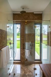 La salle de bains est pourvue d'une douche avec une porte en verre. dans l'établissement Laguna homes, à Thalang