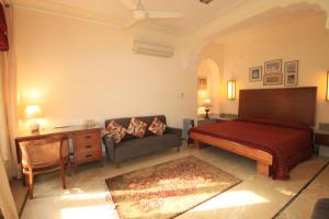 Hotel Meghniwas في جايبور: غرفة نوم بسرير واريكة ومكتب