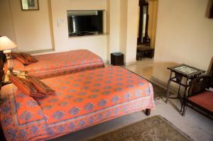 a room with two beds and a couch and a television at Hotel Meghniwas in Jaipur