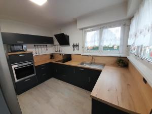 a kitchen with black cabinets and a wooden counter top at zouzoubelle in Coudekerque-Branche