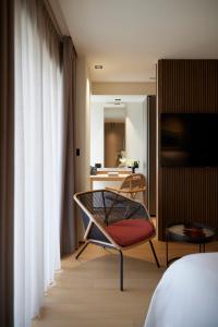 um quarto com uma cama, uma cadeira e um espelho em Dusit Suites Athens em Atenas