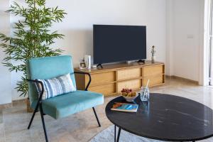 un soggiorno con tavolo, sedia e TV di Home2Book Sea View & Design Duplex Los Gigantes a Puerto de Santiago