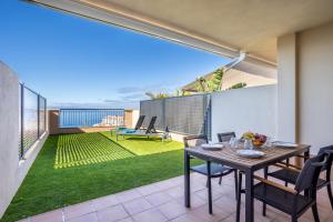 un patio con tavolo e sedie sul balcone. di Home2Book Sea View & Design Duplex Los Gigantes a Puerto de Santiago