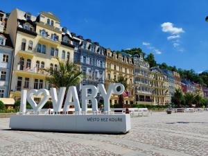 una señal para una ciudad con edificios en el fondo en Rezidence Čertovka, en Karlovy Vary