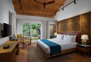 Dormitorio con cama, escritorio y TV en Larisa Resort Ashwem, en Mandrem
