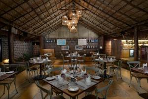 a restaurant with tables and chairs and a chandelier at Larisa Resort Ashwem in Mandrem