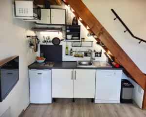 a small kitchen with white cabinets and a sink at Tiny House Chaleureuse au Style Contemporain Minimaliste in Le Tampon +24 photos