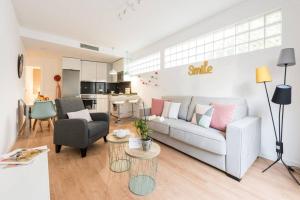 a living room with a white couch and a kitchen at Apartamento con jardin privado y portero (A) in Madrid