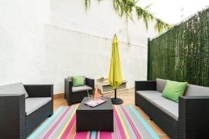 un patio con due sedie, un tavolo e un ombrellone giallo di Apartamento con jardin privado y portero (A) a Madrid