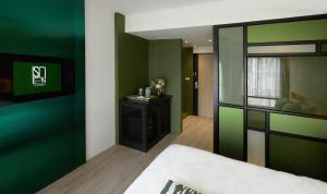 een kamer met groene muren en een bed en een spiegel bij Hotel Sapin in Pom Prap