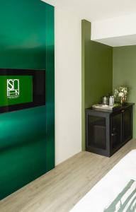een woonkamer met een groene muur en een tv bij Hotel Sapin in Pom Prap