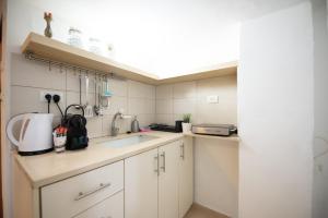 a small kitchen with white cabinets and a sink at PORT CITY HAIFA - Downtown Studio with Gallery nxt German Colony in Haifa