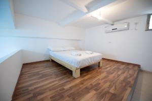 Bett in einem Zimmer mit Holzboden in der Unterkunft PORT CITY HAIFA - Downtown Studio with Gallery nxt German Colony in Haifa