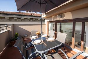 una mesa y sillas en un balcón con sombrilla en Rooftop Delight with Terrace en Lucca
