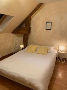 een bed met witte lakens en gele kussens in een kamer bij Gîte Utah du DOMAINE DE SAINT-VIGOR 